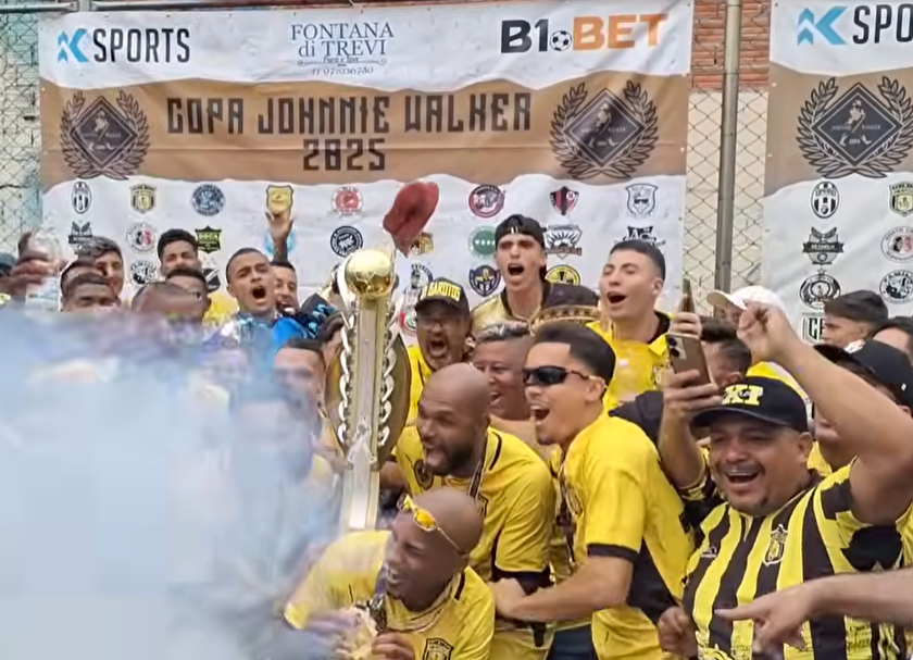 Jogadores do 11 Garotos comemoram o título da Copa Johnny Walker, erguendo o troféu em meio à torcida e celebração.