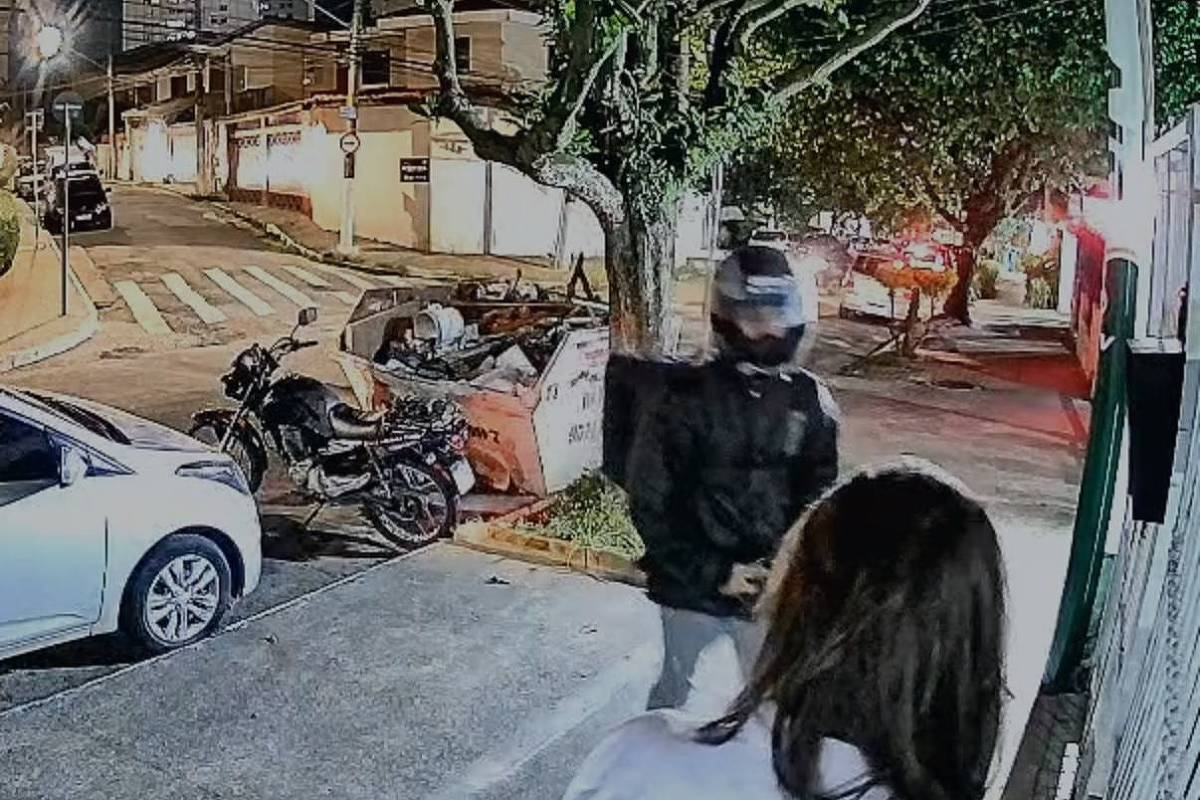 Imagem de câmera mostrando motociclista com sacola de entregas apontando arma