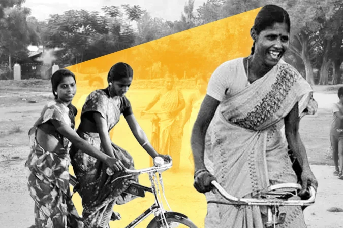 Mulheres indianas andando de bicicleta em estrada rural
