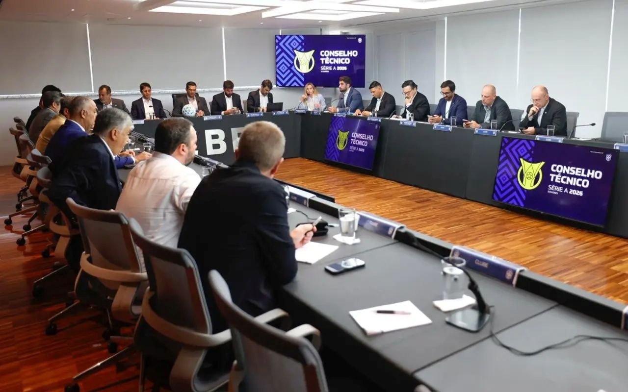 Reunião de dirigentes em mesa com documentos sobre futebol