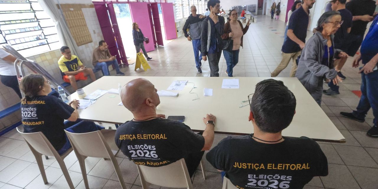 Eleitores em fila ao lado de urnas eletrônicas durante votação