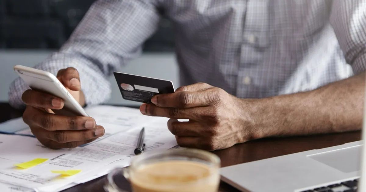 Pessoa segurando cartão de crédito e celular