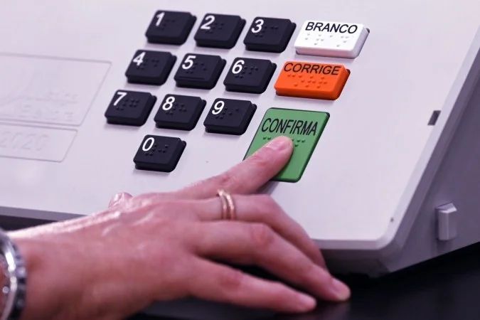 Urnas eletrônicas e mesários durante eleição