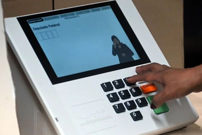Urna eletrônica com eleitores em fila