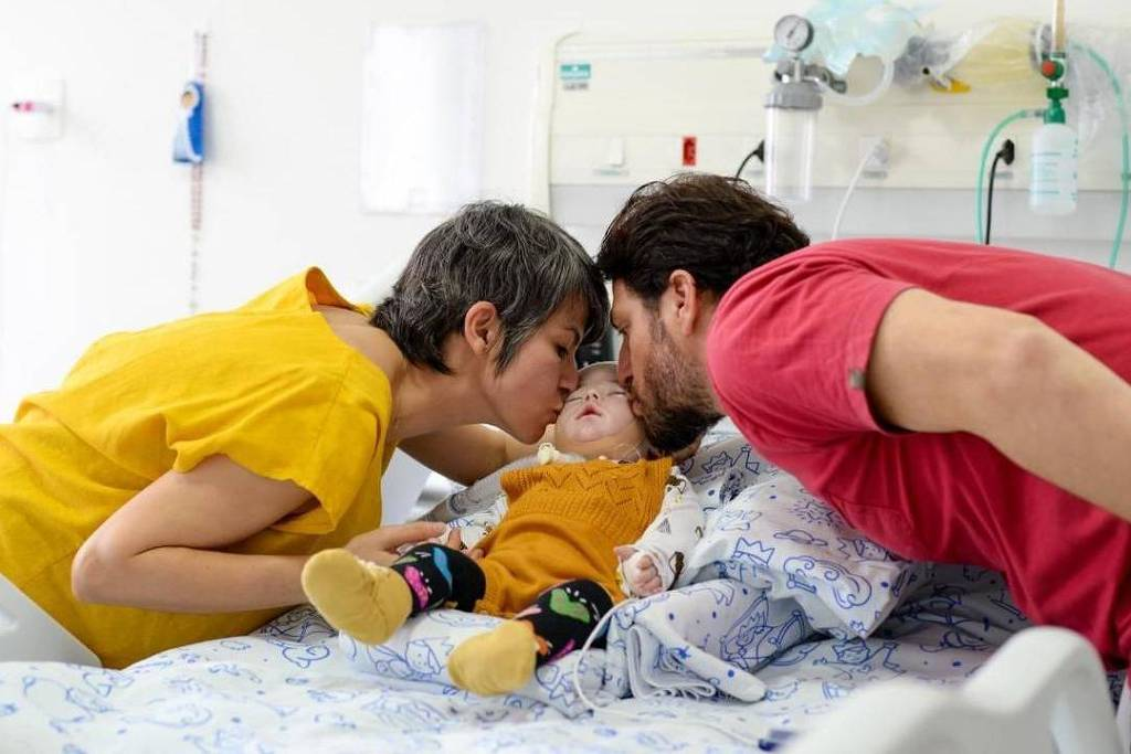 Mãe segurando recém-nascida em ambiente hospitalar