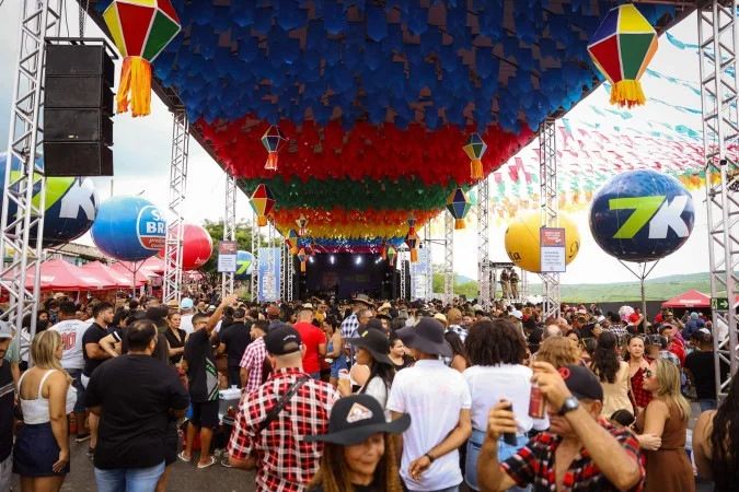 Público em festa junina com bandeirinhas ao fundo