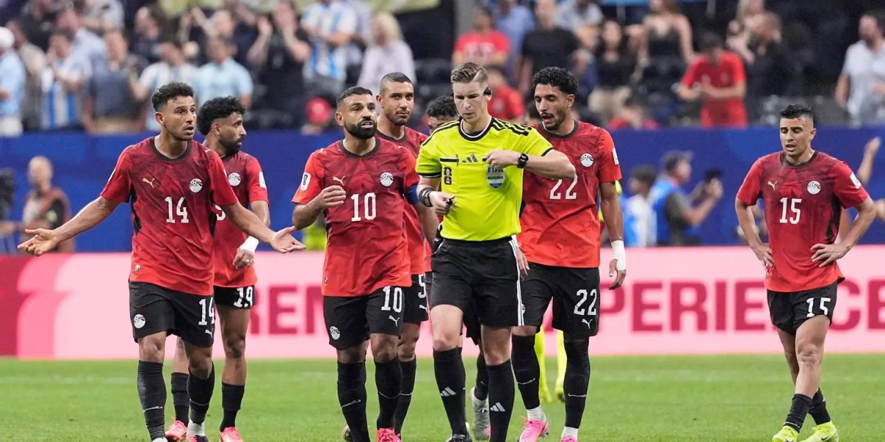Árbitro e equipe de VAR durante partida entre Argentina e Egito