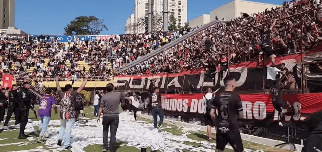 Jogadores do Unidos do Morro celebrando a vitória nos pênaltis contra o Blumenau na final da Especial de São Bernardo, com torcida festejando a conquista do título.