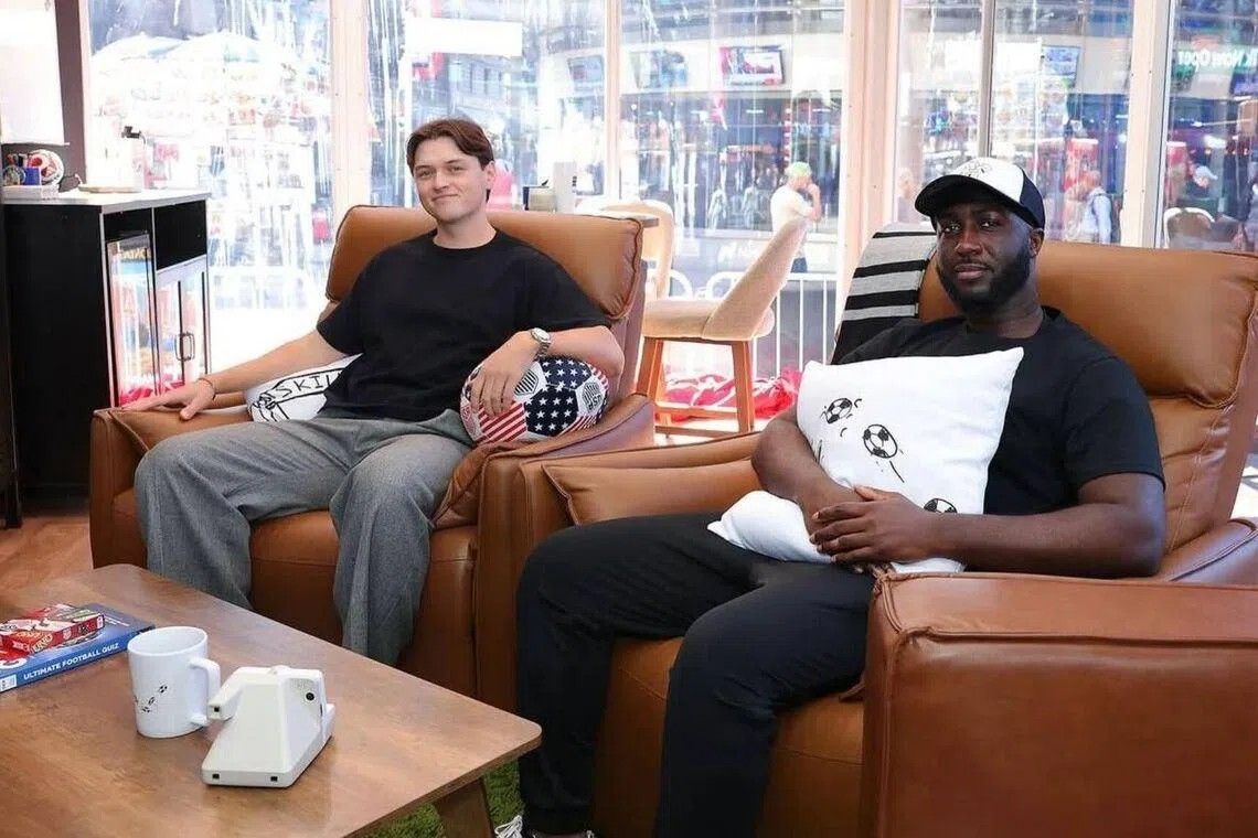 Dois criadores de conteúdo dentro de cubo de observação na Times Square