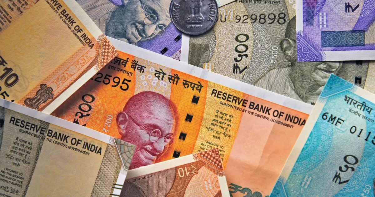 Notas indianas ao lado de gráfico de mercado