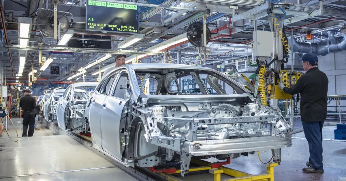 Fábrica automotiva com bandeiras dos Estados Unidos e China ao fundo