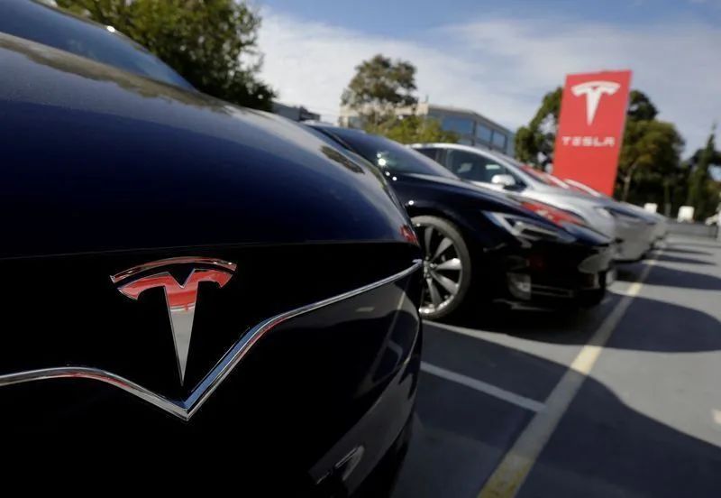 Elon Musk ao lado do logotipo da Tesla