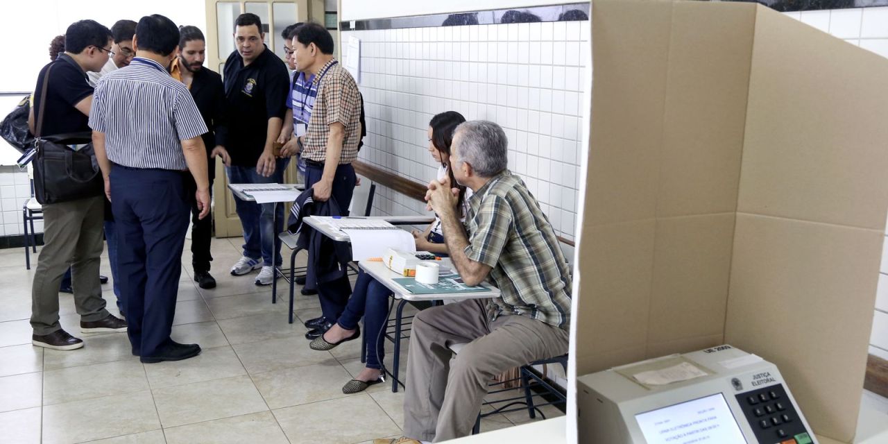 Mesários em seção eleitoral realizando identificação de eleitores