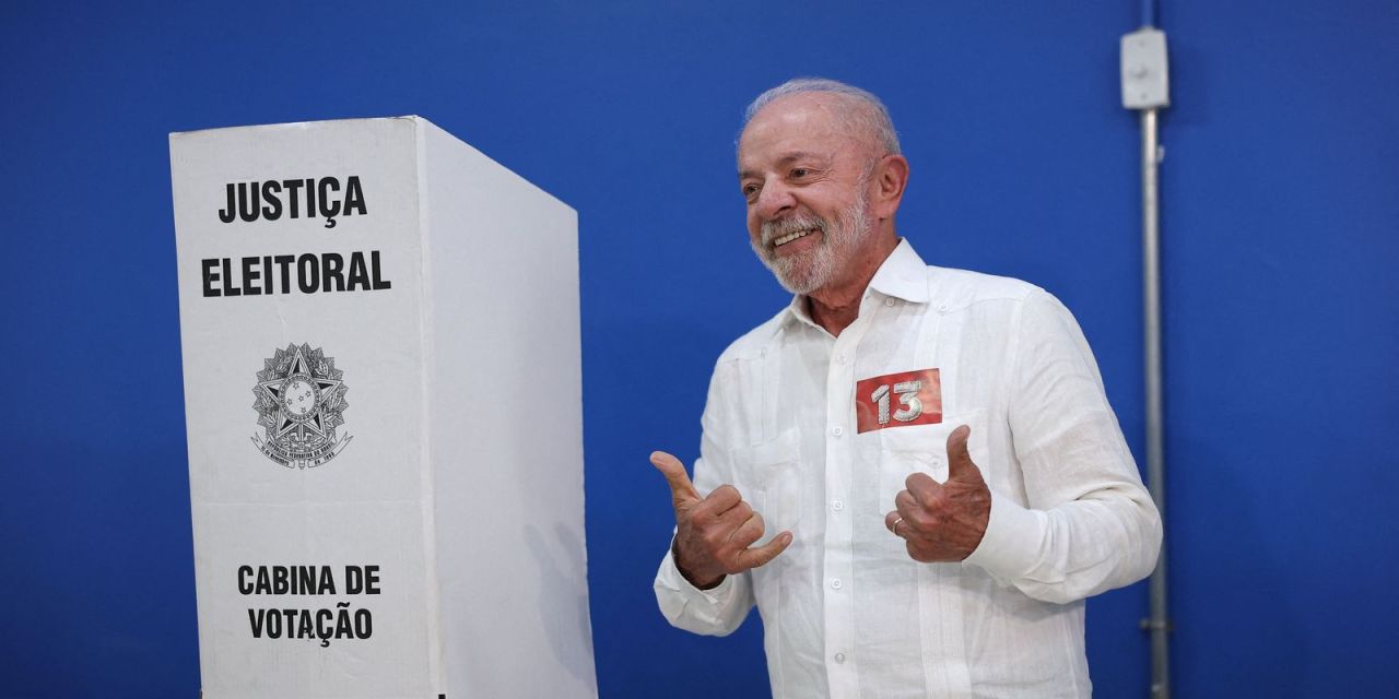 Lula segurando bandeira do Brasil ao chegar à escola de votação