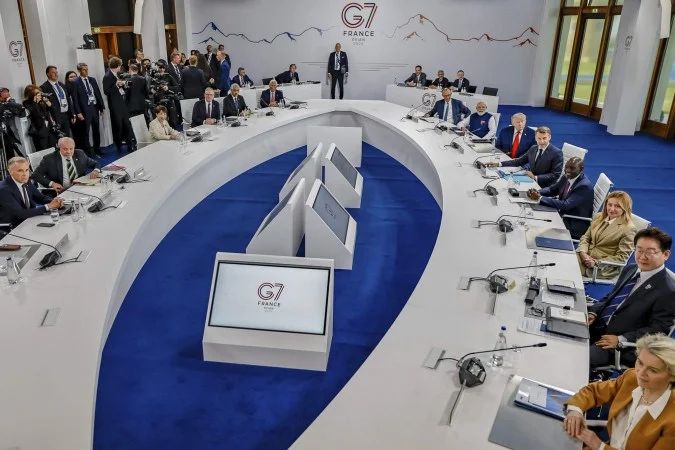 Lula e Trump se cumprimentam no corredor do hotel em Évian durante a cúpula do G7