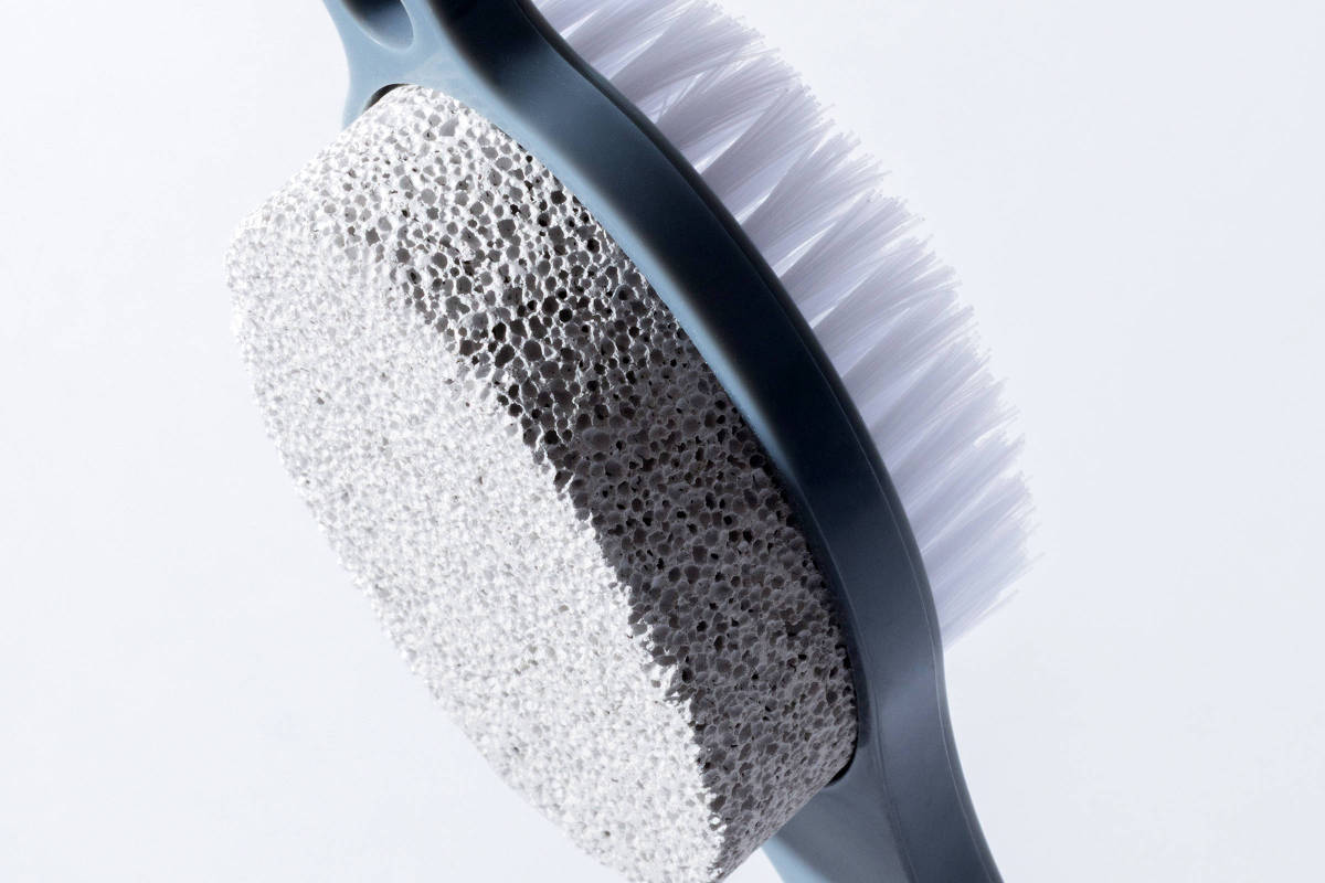 Pessoa usando pedra-pomes no calcanhar