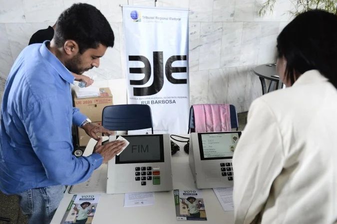 Mulheres e urna eletrônica em fila de votação