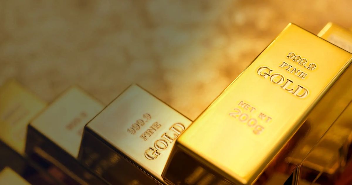 Lingotes de ouro com tela de cotações ao fundo