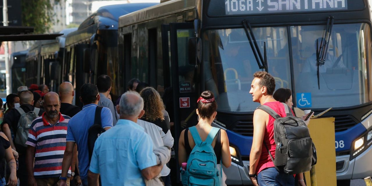 Passageiros aguardando ônibus em ponto da zona leste de São Paulo