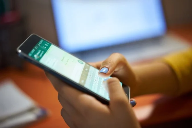 Pessoa olhando tela de smartphone com ícones de redes sociais