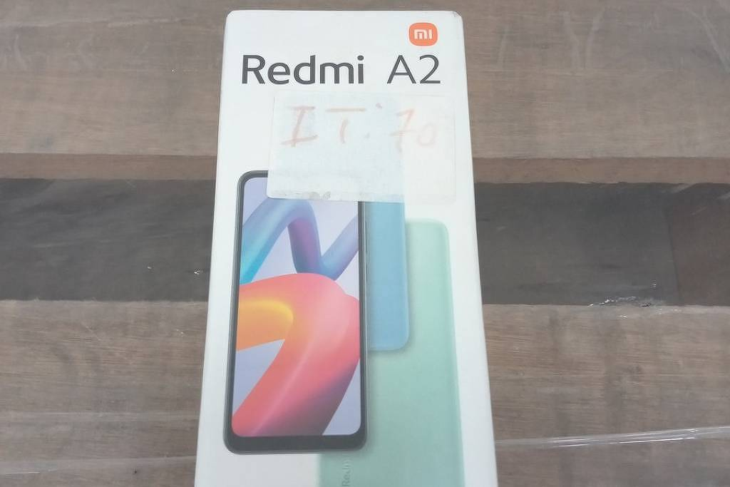 Mesa com celulares, notebooks e eletrodomésticos alinhados para leilão