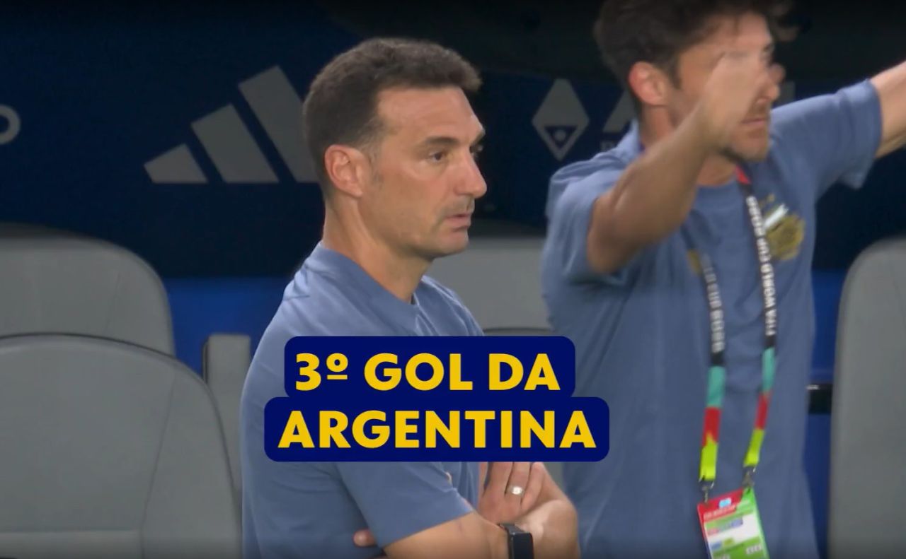 Scaloni em pé no banco de reservas observando o campo