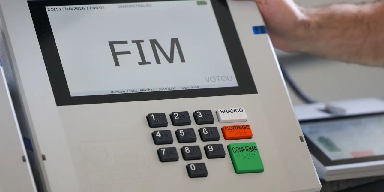 Urna eletrônica e fila de eleitores em seção eleitoral