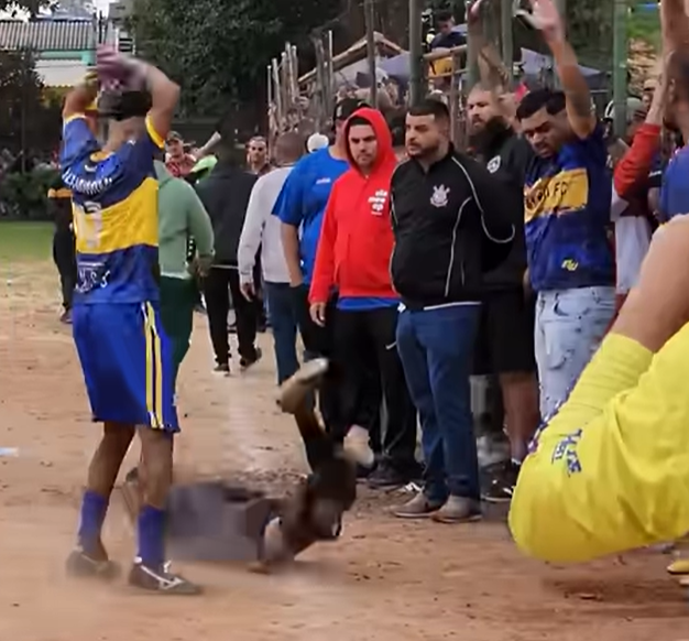 Jogadores do Sem Mimimi erguendo a taça da Copa Guto Tavares no campo da Praça Orobó em Guarulhos, com torcida ao fundo
