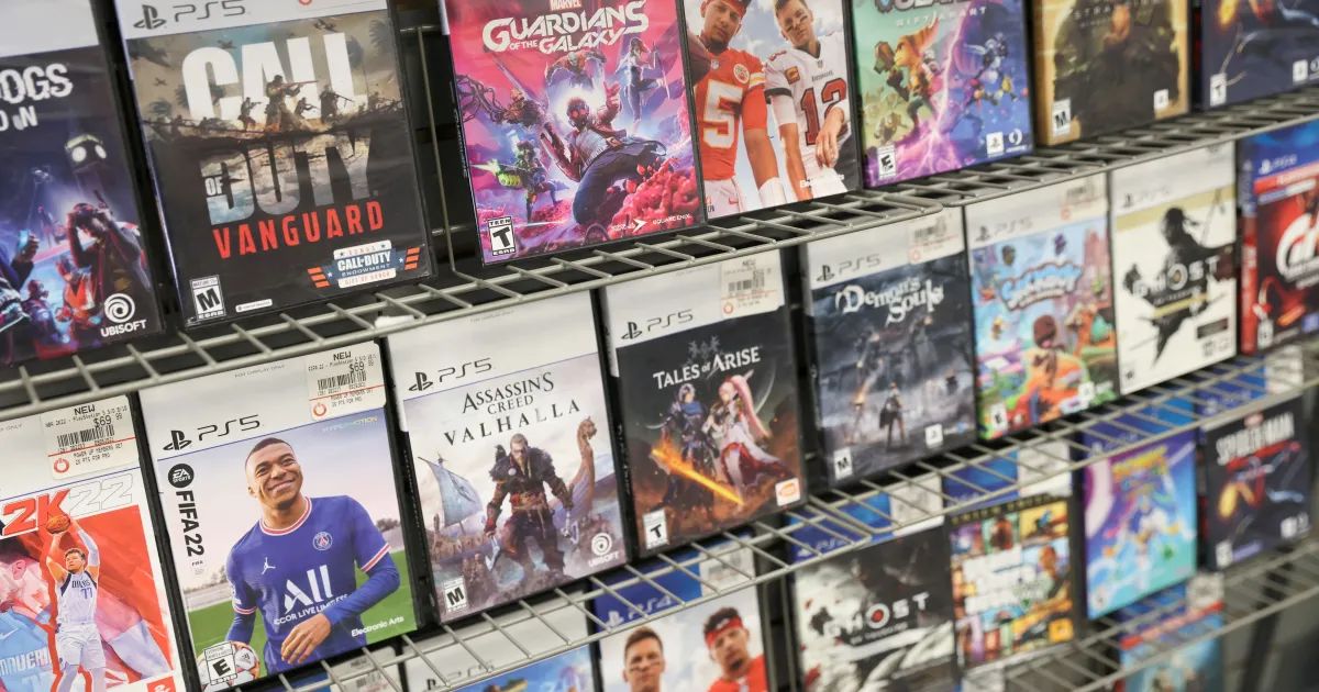 Controle PlayStation ao lado de caixas de jogos em prateleira