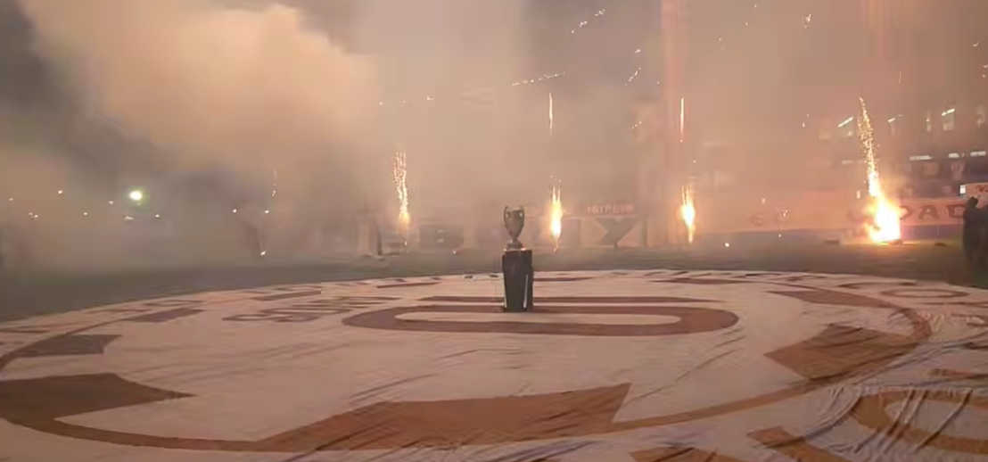 Jogadores do MEC celebrando o gol de Max na abertura da Supercopa Pioneer contra o R2 Debone, com torcidas lotadas no estádio de São Paulo.