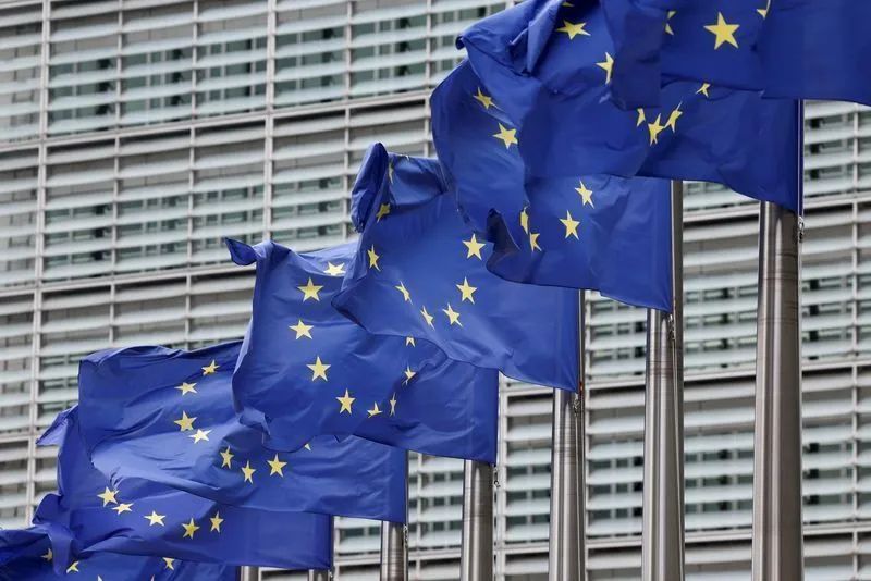 Contêineres em porto com bandeiras da UE e dos EUA ao fundo